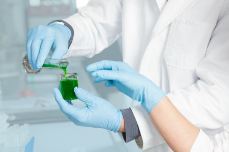 Two Chemists are decanting a green Liquid into a glass beakerの写真素材