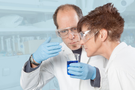 Two Chemists are smelling the blue Liquid の写真素材