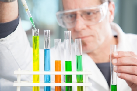 A Chemist is refilling the test tube with a yellow liquid の写真素材