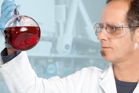 A Chemist is checking the consistency of a red Liquid の写真素材
