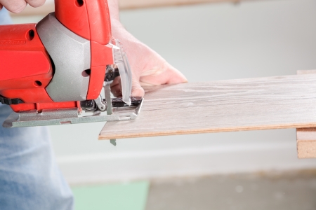 A Carpenter starts to saw a laminate plank with a jigsaw の写真素材