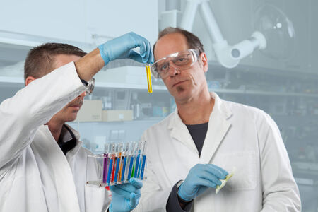 Two Chemist colleagues are appraising a yellow liquid の写真素材