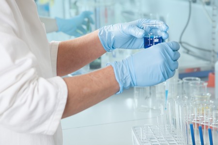 A Professor extracts a blue Liquid with a pipette の写真素材