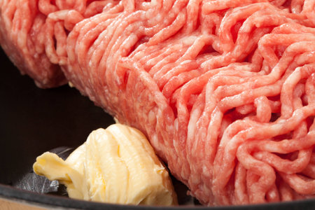 An extreme closeup from a piece of minced meat in a pan with some butter の写真素材