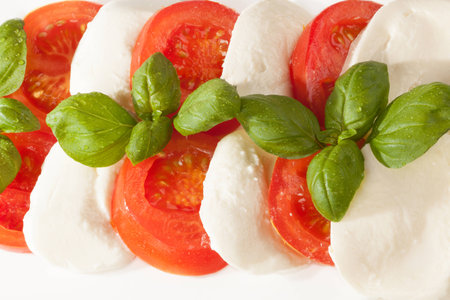 A fresh italian salad with mozzarella, tomatoes and some piece of basil の写真素材