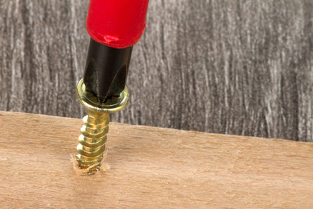 A Carpenter is using a screw driver to fix the screw in the wood panel の写真素材