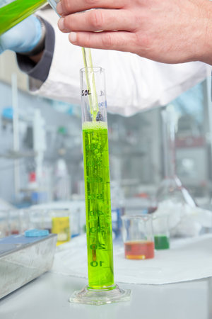 A Chemist is extracting a green liquid with a pipette の写真素材