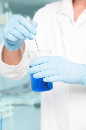 A Professor is mixing a blue liquid in a large beaker の写真素材