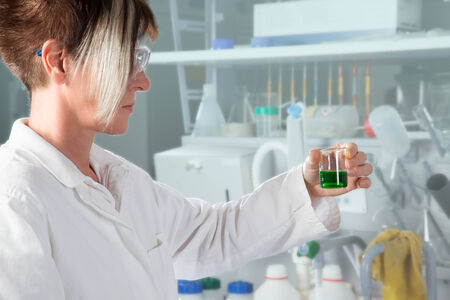 A Doctor is analyzing a beaker with some alga fluid の写真素材