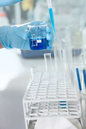 A Chemist extracts a blue fluid from a beaker の写真素材