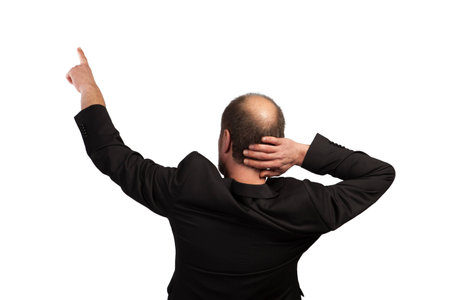 A well dressed Businessman is pointing upwards on a white background in a back view の写真素材