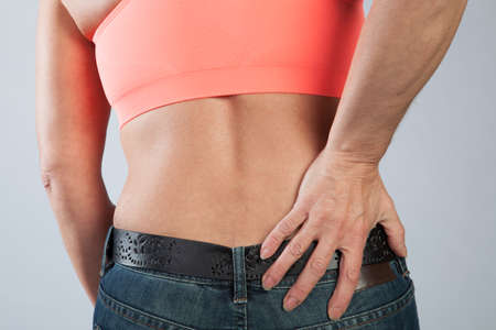 A woman has some dorsal pain and is touching her back 
