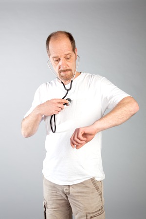 A doctor is auscultating his owen heart with a stethoscope to care by himself の写真素材