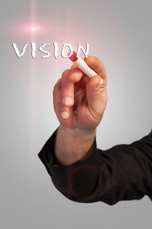 A man is writing the word vision to a virtual screen with some light effects の写真素材