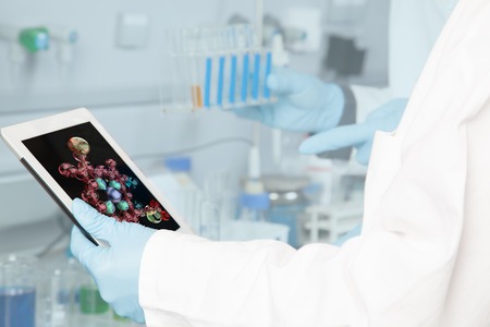 A Chemist is analyzing a chemical structure on his tablet pc の写真素材