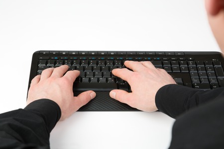 An over shoulder view from a businessman to a black Computer Keyboard, isolated on whiteの写真素材
