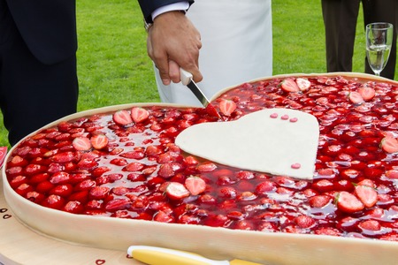 A Bright and a bridegroom a cutting the wedding cake. His hand is on top at the knife.の写真素材