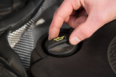 A young man is opening the oil cap from his car.の写真素材