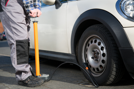 A mechanic repairs a flat tire with an atmospheric pressure pumpの写真素材