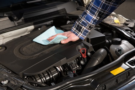 A man is cleaning his car engine with a rag.の写真素材