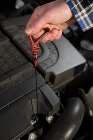 A service mechanic inspects the oil level from a car.の写真素材