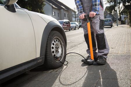A man is pumping up a car tire after a malfunctionの写真素材