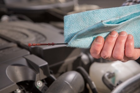A mechanic is checking the oil level from a car engine.の写真素材