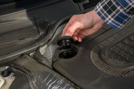 A mechanic is opening the oil cap from a car engine.の写真素材