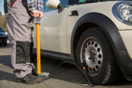 A man is refilling the car tire after a malfunction.の写真素材