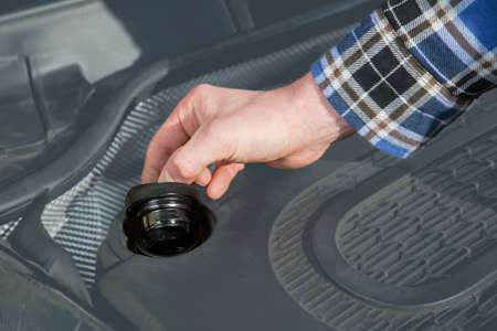 A mechanic opens the cap in the car engine block.の写真素材