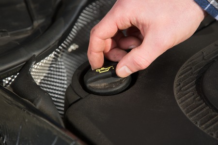 The mechanic is opening the oil cap from a car to verifying the oil level.の写真素材