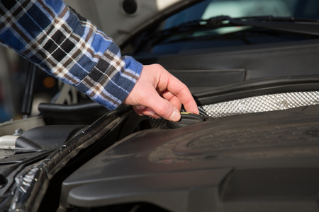 A man is opening a oil cap inside a car engine motor block.の写真素材