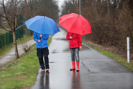 A couple is walking through the rain with umbrellas and rain cloth.の写真素材