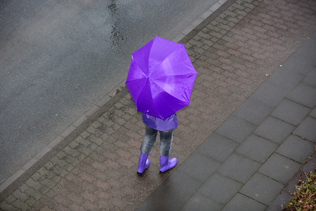 A woman is standing in the rain with an umbrella.の写真素材