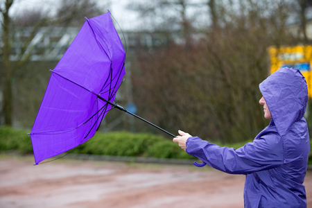 A woman is holding an umbrella in the wind.の写真素材
