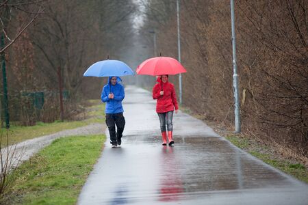 A raincoat dressed couple is walking in the rain.の写真素材