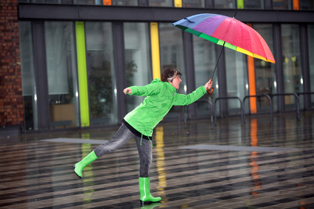 A woman is fighting against the wind in the rain with an umbrella.の写真素材