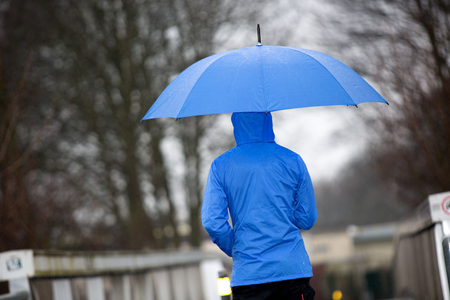 A man is walking in the rain with his umbrella and raincoat.の写真素材