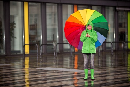 A woman is waiting in the rain with her rain cloth.の写真素材