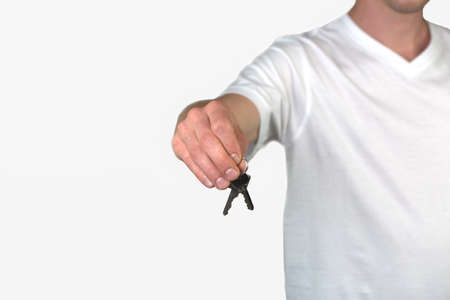 A man is holding an apartment key in his hand isolated on a grey background.の写真素材