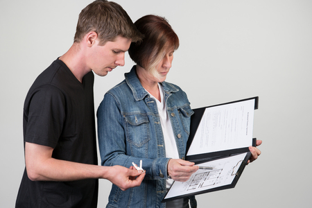A landlord explains the floor plan to the tenant. Isolated on a grey background.の写真素材