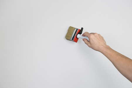 A man with a paint brush is painting the grey wall.の写真素材
