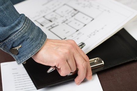 An architect is clipping some floorplans to a clipboard.
