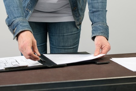 A woman is reading a document which is clipped into a clipboard.の写真素材