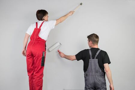 Teamwork from a couple in work dress are starting to paint a wall together.の写真素材