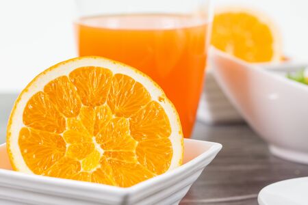 A half cutted orange fruit in a bowl infront of a glass of orange juice decorated with some other breakfast elements.の写真素材