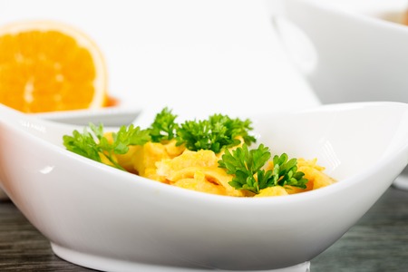 A portion of scrambled eggs in a bowl decorated with some basil.の写真素材