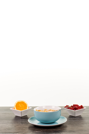 A portion of granola in a big blue cup with berrys and a sliced orange fruit in the background. A lot of copyspace available.の写真素材