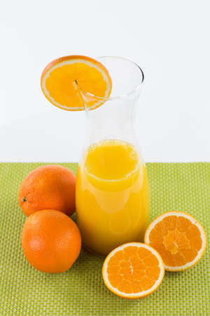 A large carafe of orange juice decorated with sliced orange fruits, isolated on a white background.の写真素材