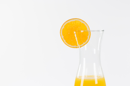 Half of a carafe with fresh orange juice, decorated with a slice of an orange fruit.の写真素材